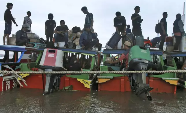 People board boats as they travel to their home villages to celebrate Eid al-Fitr holiday, at a wharf in Palembang, South Sumatra, Indonesia, Sunday, April 7, 2024. Millions of Indonesians are packing bus and train stations, airports and highways as they head to hometowns to celebrate Thursday's Eid al-Fitr festival with family. (AP Photo/Muhammad Hatta)