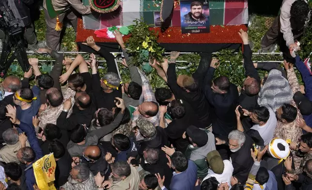 Iranian mourners try to touch the flag-draped coffins of Revolutionary Guard members killed in an airstrike widely attributed to Israel that destroyed Iran's Consulate in Syria on Monday, in a funeral procession in Tehran, Iran, Friday, April 5, 2024. The public funeral coincided with Iran's annual rally Quds Day, or Jerusalem Day, a traditional show of support for the Palestinians that has been held on the last Friday of the holy month of Ramadan since the 1979 Islamic Revolution. (AP Photo/Vahid Salemi)