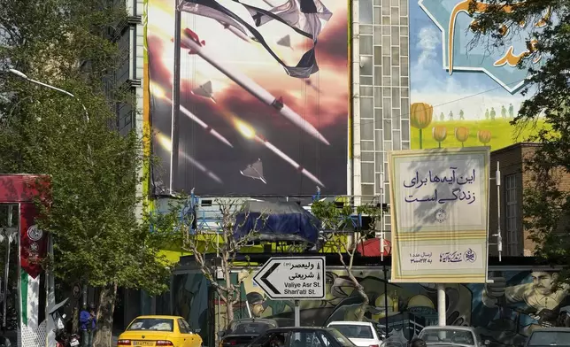 Motorbikes drive past an anti-Israeli banner on a building at the Felestin (Palestine) Square in downtown Tehran, Iran, Sunday, April 14, 2024. Israel on Sunday hailed its air defenses in the face of an unprecedented attack by Iran, saying the systems thwarted 99% of the more than 300 drones and missiles launched toward its territory. The sign in Hebrew reads: "Your next mistake will be the end of your fake country." The sign in Farsi reads: "The next slap will be harder." (AP Photo/Vahid Salemi)