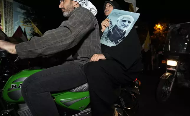 An Iranian demonstrator holds a poster of the late Revolutionary Guard Gen. Mohammad Hadi Haj Rahimi, who was killed in an airstrike widely attributed to Israel that destroyed Iran's Consulate in Syria on April 1, during an anti-Israeli gathering at the Felestin (Palestine) Square in Tehran, Iran, early Sunday, April 14, 2024. Iran launched its first direct military attack against Israel Saturday. (AP Photo/Vahid Salemi)