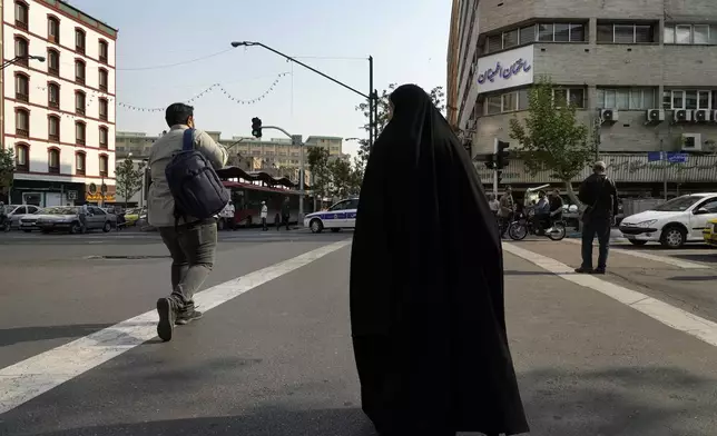 People cross an intersection in downtown Tehran, Iran, Sunday, April 14, 2024. Israel on Sunday hailed its air defenses in the face of an unprecedented attack by Iran, saying the systems thwarted 99% of the more than 300 drones and missiles launched toward its territory. (AP Photo/Vahid Salemi)