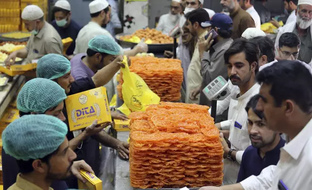 FILE - People buy sweets at a shop in preparation for the upcoming Eid al-Fitr celebrations, in Peshawar, Pakistan, Sunday, May 1, 2022. (AP Photo/Mohammad Sajjad, File)