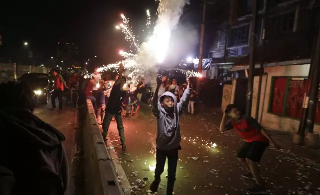 FILE - Youths light firecrackers and flares as they celebrate the end of the fasting month of Ramadan on a street in Jakarta, Indonesia, Tuesday, June 4, 2019. Islam follows a lunar calendar and so Ramadan and Eid cycle through the seasons. In 2024, the first day of Eid al-Fitr is expected to be on or around April 10; the exact date may vary among countries and Muslim communities. (AP Photo/Dita Alangkara, File)