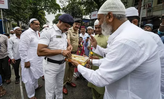 FILE - Muslims offer sweets to police officers on duty after offering prayers on Eid al-Fitr in Kolkata, India, Tuesday, May 3, 2022. Muslims are the largest minority group in the Hindu-majority nation. (AP Photo/Bikas Das, File)