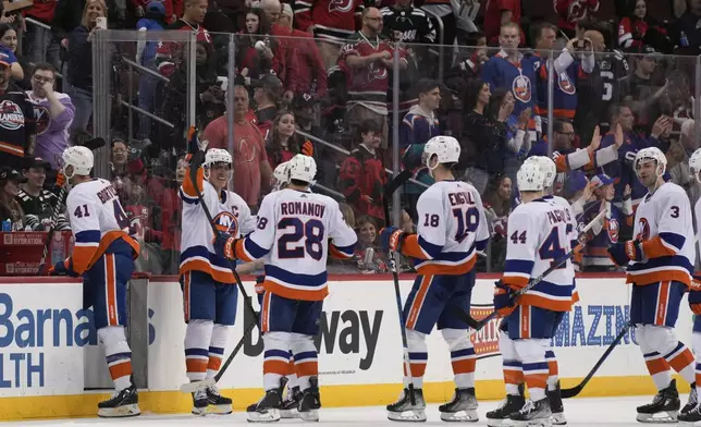 New York Islanders' Anders Lee, second from left, celebrates with teammates as they come off the ice after an NHL hockey game against the New Jersey Devils in Newark, N.J., Monday, April 15, 2024. (AP Photo/Seth Wenig)
