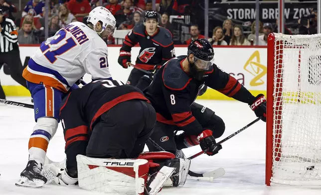 Carolina Hurricanes' Brent Burns (8) tries to stop the puck as it slips by goaltender Frederik Andersen (31) as New York Islanders' Kyle Palmieri (21) watches his goal during the first period in Game 2 of an NHL hockey Stanley Cup first-round playoff series in Raleigh, N.C., Monday, April 22, 2024. (AP Photo/Karl B DeBlaker)