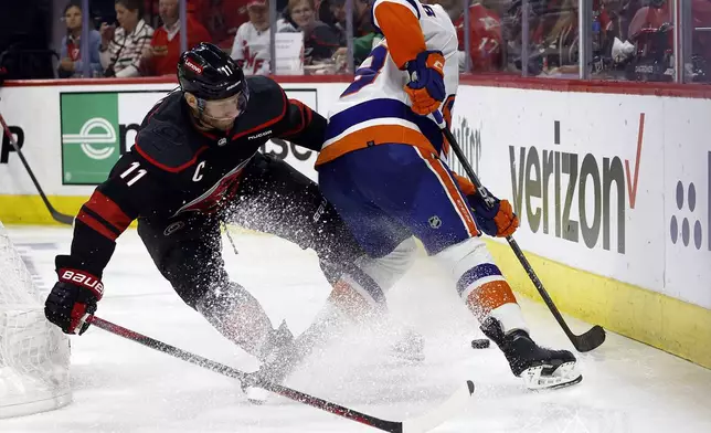Carolina Hurricanes' Jordan Staal (11) battles with New York Islanders' Noah Dobson (8) for the puck during the second period in Game 2 of an NHL hockey Stanley Cup first-round playoff series in Raleigh, N.C., Monday, April 22, 2024. (AP Photo/Karl B DeBlaker)