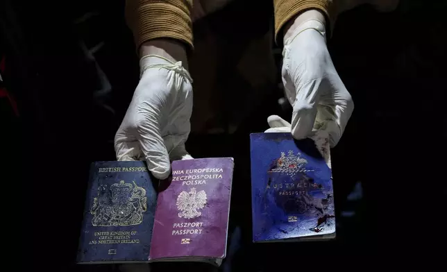 FILE - A man displays blood-stained British, Polish, and Australian passports after an Israeli airstrike, in Deir al-Balah, Gaza Strip, World Central Kitchen and a few other aid groups suspended operations in Gaza, after seven aid workers were killed by airstrikes. Yet despite the danger, many of the largest organizations barely slowed down. Hunger has become commonplace in Gaza amid the war with Israel, and U.N. officials warn that famine is increasingly likely in northern Gaza. (AP Photo/Abdel Kareem Hana, File)