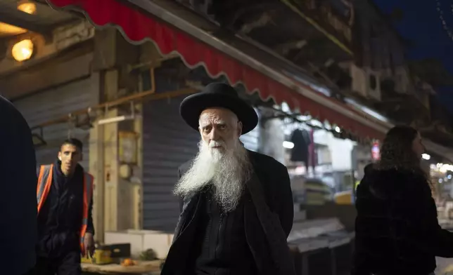An elderly ultra-Orthodox Jewish man looks on as he walks in the Mahane Yehuda market in Jerusalem, Sunday, April 14, 2024. Israel on Sunday hailed its air defenses in the face of an unprecedented attack by Iran, saying the systems thwarted 99% of the more than 300 drones and missiles launched toward its territory. (AP Photo/Leo Correa)