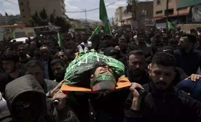 Mourners carry the body of Hamas local commander Mohammad Daraghmeh, 26, wrapped with a Hamas flag, during his funeral in the West Bank city of Tubas, Friday, April 12, 2024. Two Palestinians were killed early Friday in confrontations with Israeli forces in the Israeli-occupied West Bank, Palestinian medics and the Israeli military said. The Islamic militant group Hamas said one of those killed was a local commander. (AP Photo/Nasser Nasser)