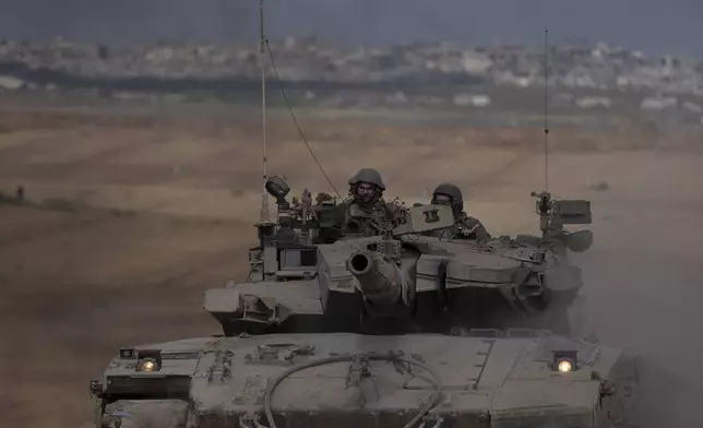 Israeli soldiers move on the top of a tank near the Israeli-Gaza border, as seen from southern Israel, Tuesday, April 9, 2024. (AP Photo/Leo Correa)