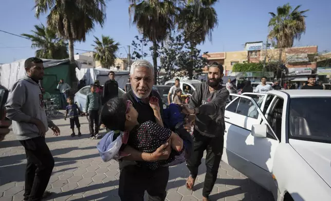 A Palestinian man carries a wounded boy following an Israeli bombardment in the Maghazi refugee camp, central Gaza Strip, Tuesday, April 16, 2024. Several killed in a strike in Maghazi camp in Central Gaza on Tuesday. (AP Photo/Abdel Kareem Hana)