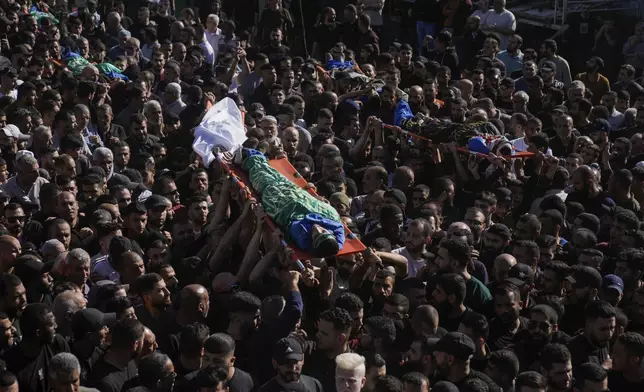 Mourners carry the bodies of Palestinians, some are draped in the Hamas and Islamic Jihad militant group flags during their funeral in the Nur Shams refugee camp, near the West Bank town of Tulkarem, Sunday, April 21, 2024. The Palestinian Red Crescent rescue service said 14 bodies have been recovered from the Nur Shams urban refugee camp since an Israeli military operation began in the area Thursday night. The Islamic Jihad militant group confirmed the deaths of three members. Another killed was a 15-year-old boy. The Israeli army said its forces killed 10 militants in the camp and surrounding areas while eight suspects were arrested. (AP Photo/Majdi Mohammed)