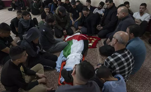 Mourners take the last look at the body of Palestinian Mohammad Shahmawi, 22, at a mosque in the West Bank refugee camp of al-Faraa, Friday, April 12, 2024. Two Palestinians were killed early Friday in confrontations with Israeli forces in the Israeli-occupied West Bank, Palestinian medics and the Israeli military said. The Islamic militant group Hamas said one of those killed was a local commander. (AP Photo/Nasser Nasser)