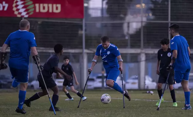 Israel Amputee Football Team player, Ben Binyamin, center, prepares to kick the ball during practice session in Ramat Gan, Thursday, April 11, 2024. During the Oct. 7 attack by Hamas militants at the Tribe of Nova music festival, Binyamin, 29, raced into an air raid shelter, but attackers fired shots and then threw in grenades. He was seriously wounded; his right leg was blown off. He was left for dead. (AP Photo/Leo Correa)