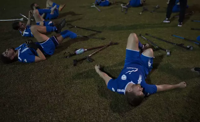 The soccer player of Israel Amputee Football Team, Ben Binyamin, right, stretches after a practice session in Ramat Gan, Thursday, April 11, 2024. The team offers players the excitement of competition, an outlet for their energies and the healing powers of sport, of overcoming the mental and physical challenges of disability. (AP Photo/Leo Correa)