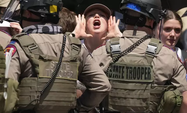A pro-Palestinian protester yells as state troopers stand during a protest at the University of Texas in Austin, Texas, Monday April, 29, 2024. (Jay Janner/Austin American-Statesman via AP)