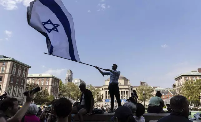Columbia sophomore, David Lederer, waves a large flag of Israel outside the student protest encampment on the Columbia University campus, Monday, April 29, 2024, in New York. Protesters of the war in Gaza who are encamped at Columbia University have defied a deadline to disband with chants, clapping and drumming. (AP Photo/Stefan Jeremiah)