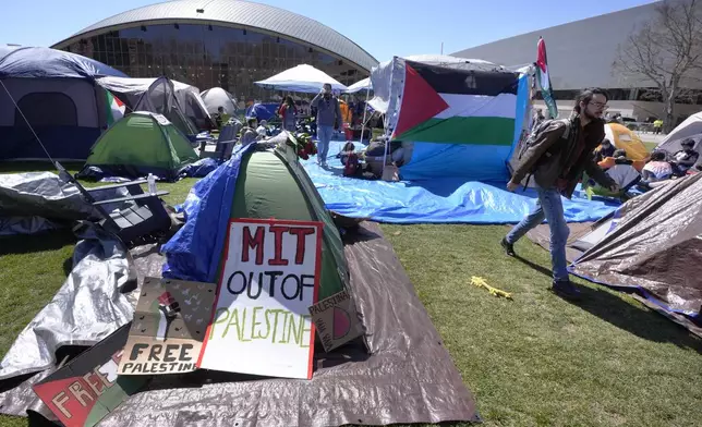 A passer-by, right, walks through an encampment of tents, Thursday, April 25, 2024, on the Massachusetts Institute of Technology campus, in Cambridge, Mass. Students at MIT set up the encampment of tents on the campus to protest what they said was MIT's failure to call for an immediate ceasefire in Gaza and to cut ties to Israel's military. (AP Photo/Steven Senne)