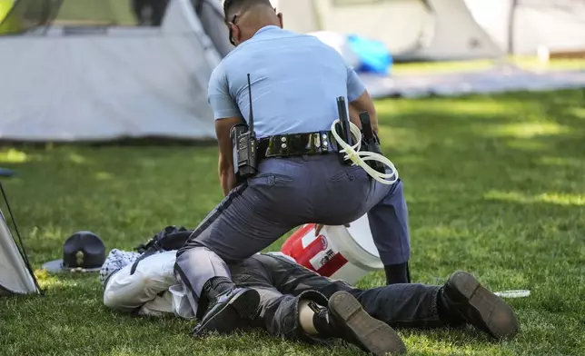 A Georgia State Patrol officer detains a protester on the campus of Emory University during a pro-Palestinian demonstration Thursday, April 25, 2024, in Atlanta. (AP Photo/Mike Stewart)