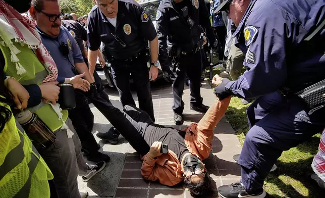A University of Southern California protester is detained by USC Department of Public Safety officers during a pro-Palestinian occupation at the campus' Alumni Park on Wednesday, April 24, 2024 in Los Angeles. (AP Photo/Richard Vogel)