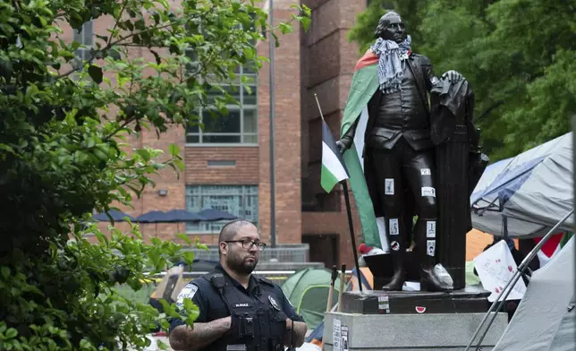 A George Washington University police officer stands near the statue of George Washington in the University Yard as student protest the Israel-Hamas war, at George Washington University in Washington, Saturday, April 27, 2024. (AP Photo/Cliff Owen)