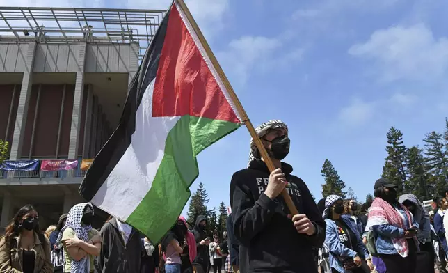 A Pro-Palestinian protester holds a Palestinian flag while in front of Sproul Hall during a protest on the campus of UC Berkeley in Berkeley, Calif., on Monday, April 22, 2024. Hundreds of pro-Palestinian protesters staged a demonstration in front of Sproul Hall where they set up a tent encampment and are demanding a permanent cease-fire in the war between Israel and Gaza. (Jose Carlos Fajardo/Bay Area News Group via AP)
