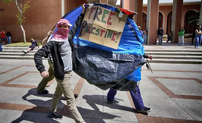 FILE - University of Southern California protesters carry a tent around Alumni Park on the University of Southern California to keep security from removing it during a pro-Palestinian occupation, Wednesday, April 24, 2024, in Los Angeles. (AP Photo/Richard Vogel, File)