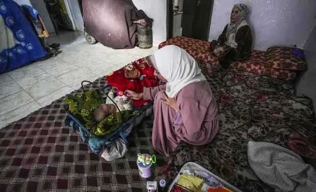Rola Saqer plays with her baby Massa Mohammad Zaqout in her parents' home in Nuseirat refugee camp, central Gaza, Thursday, April 4, 2024. Zaqout was born Oct. 7, the day the Israel- Hamas war erupted. Mothers who gave birth in the Gaza Strip that day fret that their 6-month-old babies have known nothing but brutal war, characterized by a lack of baby food, unsanitary shelter conditions and the crashing of airstrikes. (AP Photo/Abdel Kareem Hana)