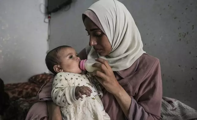 Rola Saqer feeds her baby Massa Mohammad Zaqout in her parents' home in Nuseirat refugee camp, central Gaza, Thursday, April 4, 2024. Zaqout was born Oct. 7, the day the Israel- Hamas war erupted. Mothers who gave birth that day fret that their 6-month-old babies have known nothing but brutal war, characterized by a lack of baby food, unsanitary shelter conditions and the crashing of airstrikes. (AP Photo/Abdel Kareem Hana)