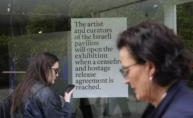 People stand in front of the closed Israeli national pavilion at the Biennale contemporary art fair in Venice, Italy, Tuesday, April 16, 2024. The sign announces that the artist and curators representing Israel at this year's Venice Biennale won't open the Israeli pavilion until there is a cease-fire in Gaza and an agreement to release hostages taken Oct. 7. (AP Photo/Luca Bruno)