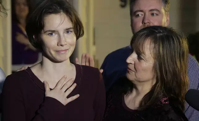 FILE - Amanda Knox, left, talks to reporters as her mother, Edda Mellas, right, looks on outside Mellas' home in Seattle, Friday, March 27, 2015. Amanda Knox faces yet another trial for slander in a case that could remove the last remaining guilty verdict against her eight years after Italy's highest court definitively threw out her conviction for the murder of her 21-year-old British roommate, Meredith Kercher. (AP Photo/Ted S. Warren, file)