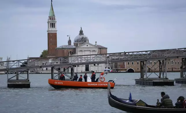 Coastguard police passes in front of on a 170-meter long floating bridge set on the occasion of the Pope Francis' visit in Venice, Italy, Saturday, April 27, 2024. Pope Francis will visit the lagoon city on Sunday, April 28. (AP Photo/Alessandra Tarantino)