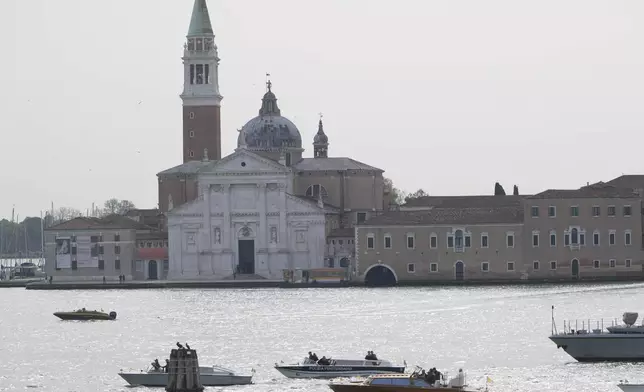 Pope Francis, aboard a motorboat foreground, passes past the Church of San Giorgio Maggiore upon his arrival in Venice, Italy, Sunday, April 28, 2024. The Pontiff arrived for his first-ever visit to the lagoon town including the Vatican pavilion at the 60th Biennal of Arts. (AP Photo/Alessandra Tarantino)