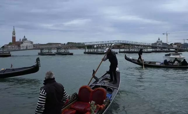 Gondolas pass in front of on a 170-meter long floating bridge set up on the occasion of the Pope Francis' visit in Venice, Italy, Saturday, April 27, 2024. Pope Francis will visit the lagoon city on Sunday, April 28. (AP Photo/Alessandra Tarantino)
