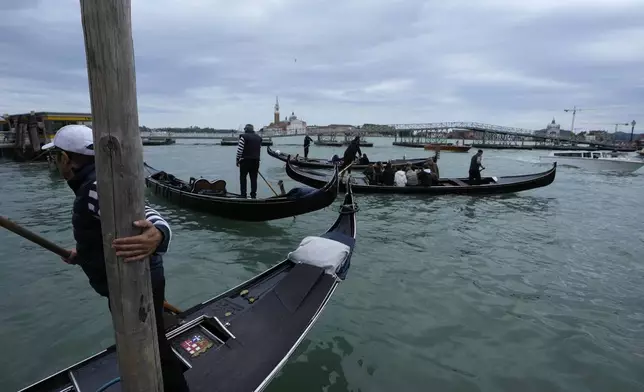 Gondolas passes in front of a 170-meter long floating bridge set up on the occasion of the Pope Francis' visit in Venice, Italy, Saturday, April 27, 2024. Pope Francis will visit the lagoon city on Sunday, April 28. (AP Photo/Alessandra Tarantino)