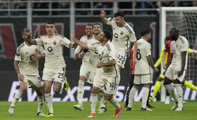 Roma's Gianluca Mancini, left, celebrates with his teammates after he scored his side's first goal during the Europa League quarterfinal first leg soccer match between AC Milan and Roma at the San Siro Stadium, in Milan, Italy, Thursday, April 11, 2024. (AP Photo/Antonio Calanni)
