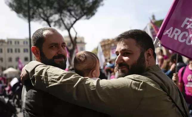 Stefano, left, and Alessandro pose for a photo with their daughter during a pro-surrogacy flash-mob in Rome, Friday, April 5, 2024. The rally was organised to counter proposals by Italy's hard-right-led government to make it a crime for Italians to try to use surrogates abroad, even in countries where the practice is legal. (AP Photo/Alessandra Tarantino)