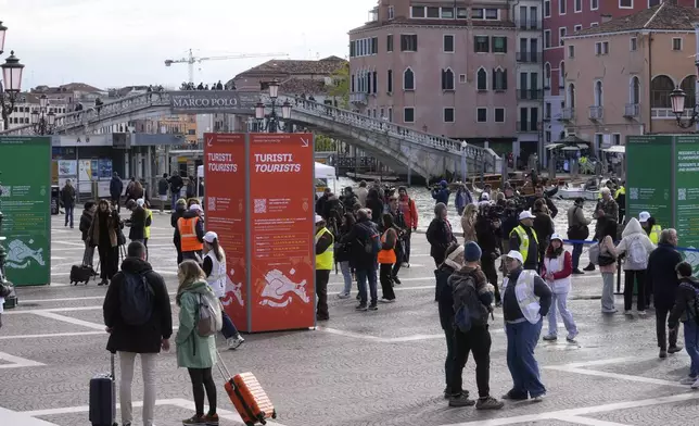 Stewards check tourists QR code access outside the main train station in Venice, Italy, Thursday, April 25, 2024. The fragile lagoon city of Venice begins a pilot program Thursday to charge daytrippers a 5 euro entry fee that authorities hope will discourage tourists from arriving on peak days. The daytripper tax is being tested on 29 days through July, mostly weekends and holidays starting with Italy's Liberation Day holiday Thursday. Officials expect some 10,000 people will pay the fee to access the city on the first day, downloading a QR code to prove their payment, while another 70,000 will receive exceptions, for example, because they work in Venice or live in the Veneto region. (AP Photo/Luca Bruno)