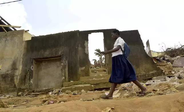A school girl walks past houses that were demolished on public health grounds in the Gesco neighborhood of Abidjan, Ivory Coast, Wednesday, Feb. 28, 2024. Rapid urbanisation has led to a population boom and housing shortages in Abidjan, where nearly one in five Ivorians reside, many of them in low-income, crowded communes like the ones in the Gesco and Sebroko districts being demolished on public health grounds. (AP Photo/Diomande Ble Blonde)