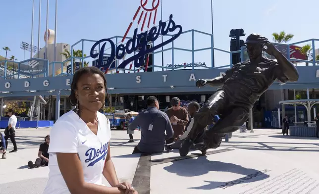 Ayo Robinson, the granddaughter of baseball great Jackie Robinson, pauses next to a sculpture of her grandfather on Jackie Robinson Day before a baseball game between the Los Angeles Dodgers and the Washington Nationals at Dodgers Stadium in Los Angeles, Monday, April 15, 2024. (AP Photo/Damian Dovarganes)