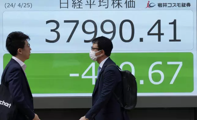 People walk in front of an electronic stock board showing Japan's Nikkei 225 index at a securities firm Thursday, April 25, 2024, in Tokyo. (AP Photo/Eugene Hoshiko)