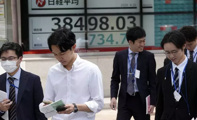People walk near an electronic stock board showing Japan's Nikkei 225 index at a securities firm Tuesday, April 16, 2024, in Tokyo. (AP Photo/Eugene Hoshiko)