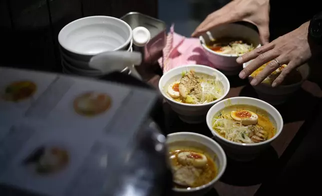A staff member prepares to serve noodles for participants of Tokyo Ramen Tours at Syuuichi, which means "once a week," featuring curry-flavored ramen, at Shibuya district on April 2, 2024, in Tokyo. (AP Photo/Eugene Hoshiko)