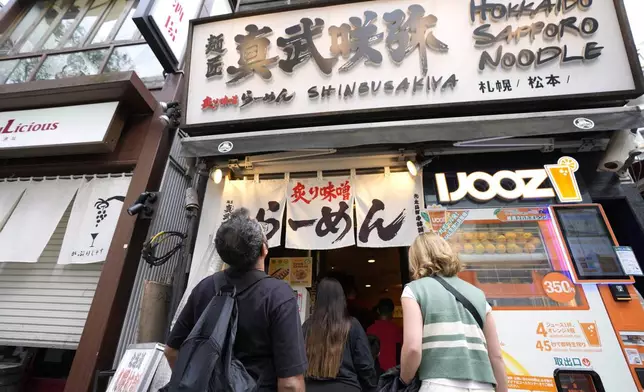 Participants of Tokyo Ramen Tours enter Shinbusakiya, a ramen shop which offers "Hokkaido classics," at Shibuya district on April 2, 2024, in Tokyo. (AP Photo/Eugene Hoshiko)