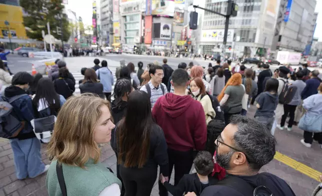 Frank Striegl, center, a guide of Tokyo Ramen Tours, leads several participants of a ramen tasting tour near Shibuya pedestrian crossing at Shibuya district on April 2, 2024, in Tokyo. (AP Photo/Eugene Hoshiko)