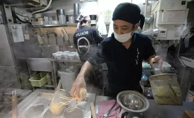 Chefs prepare noodles for participants of Tokyo Ramen Tours at Syuuichi, which means "once a week," featuring curry-flavored ramen, at Shibuya district on April 2, 2024, in Tokyo. (AP Photo/Eugene Hoshiko)