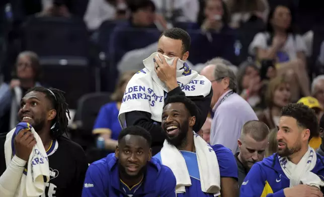 Golden State Warriors' Stephen Curry, back, laughs after a slam dunk late in the second half of an NBA basketball game against the Utah Jazz in San Francisco on Sunday, April 14, 2024. (Carlos Avila Gonzalez/San Francisco Chronicle via AP)
