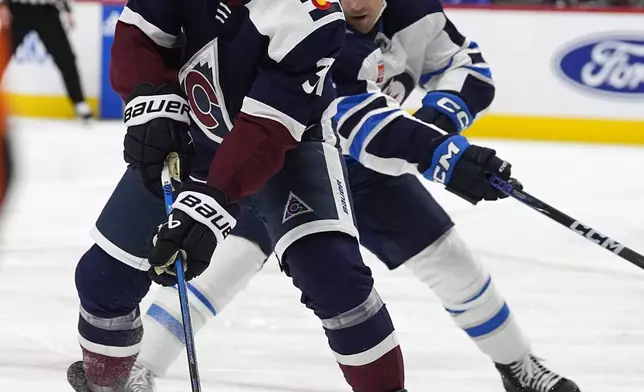 Colorado Avalanche center Casey Mittelstadt, left, looks to pass the puck as Winnipeg Jets defenseman Neal Pionk, right, covers in the first period of an NHL hockey game Saturday, April 13, 2024, in Denver. (AP Photo/David Zalubowski)