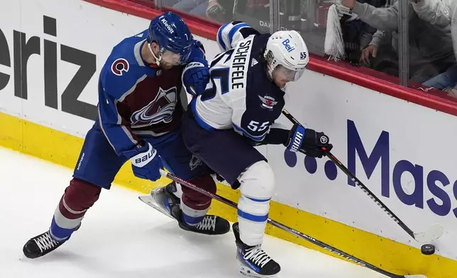 Winnipeg Jets center Mark Scheifele, right, tries to control the puck next to Colorado Avalanche defenseman Devon Toews during the first period of Game 3 of an NHL hockey Stanley Cup first-round playoff series Friday, April 26, 2024, in Denver. (AP Photo/David Zalubowski)